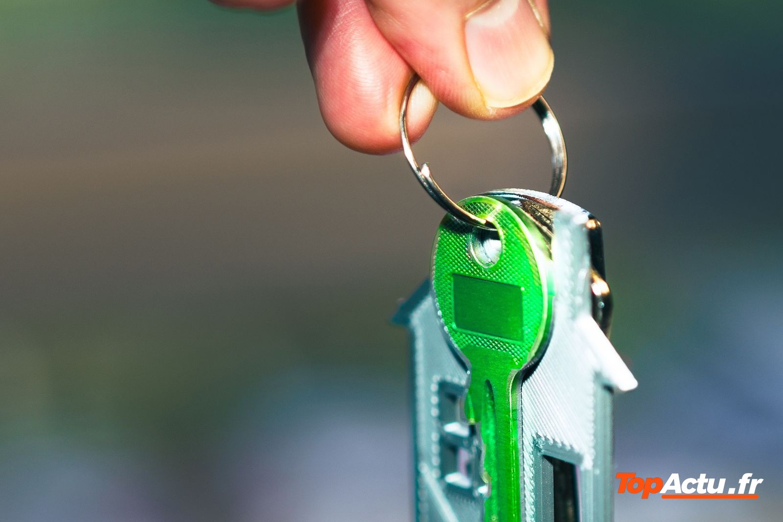 Main qui tient une clé avec un porte-clés en forme de maison