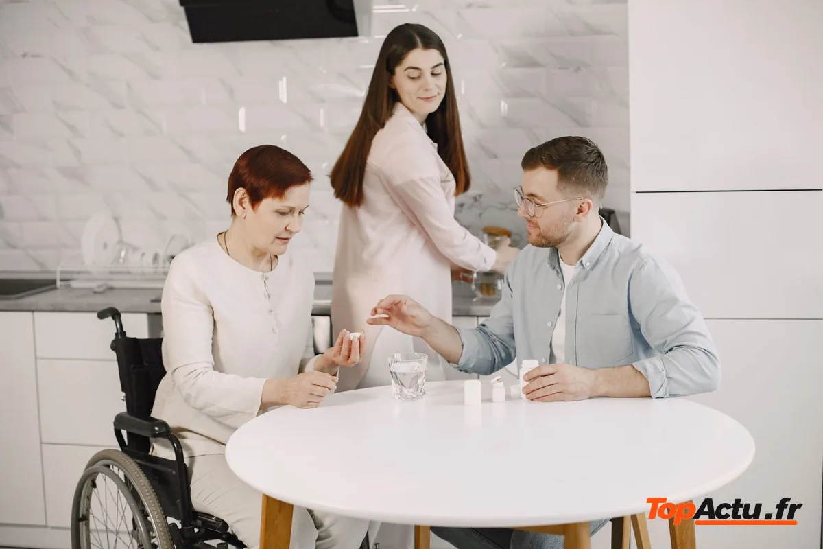 Une aide à domicile et un proche autour d'une table avec une femme en fauteuil roulant