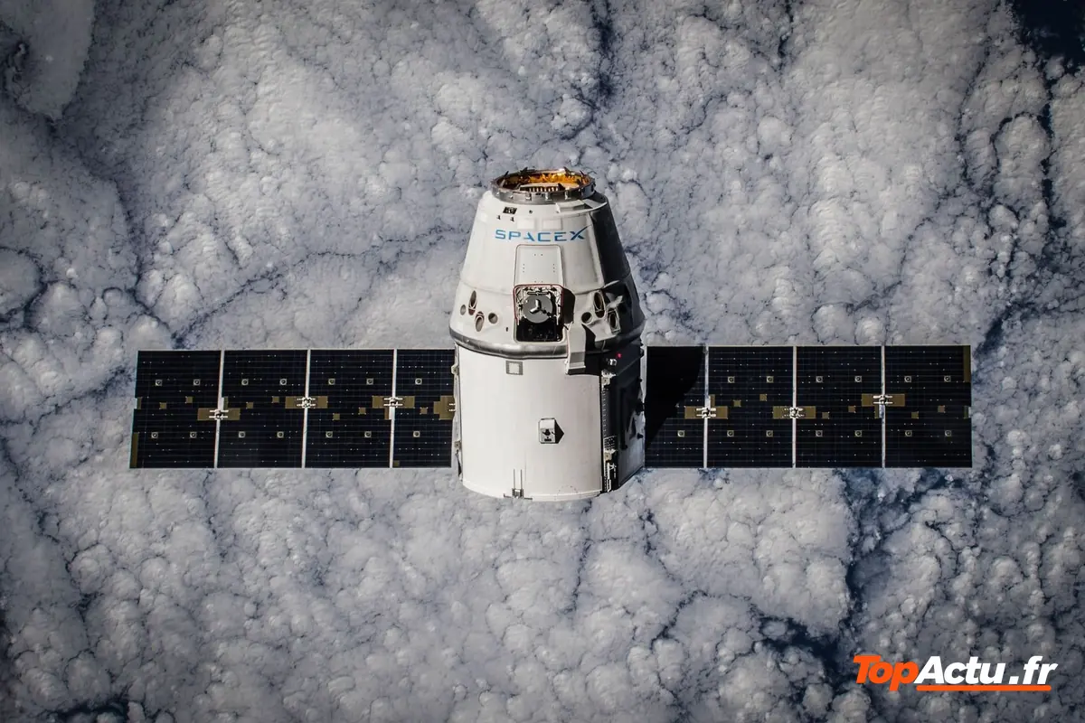 Une capsule spatiale aux panneaux solaires déployés vue au-dessus d'un tapis de nuages
