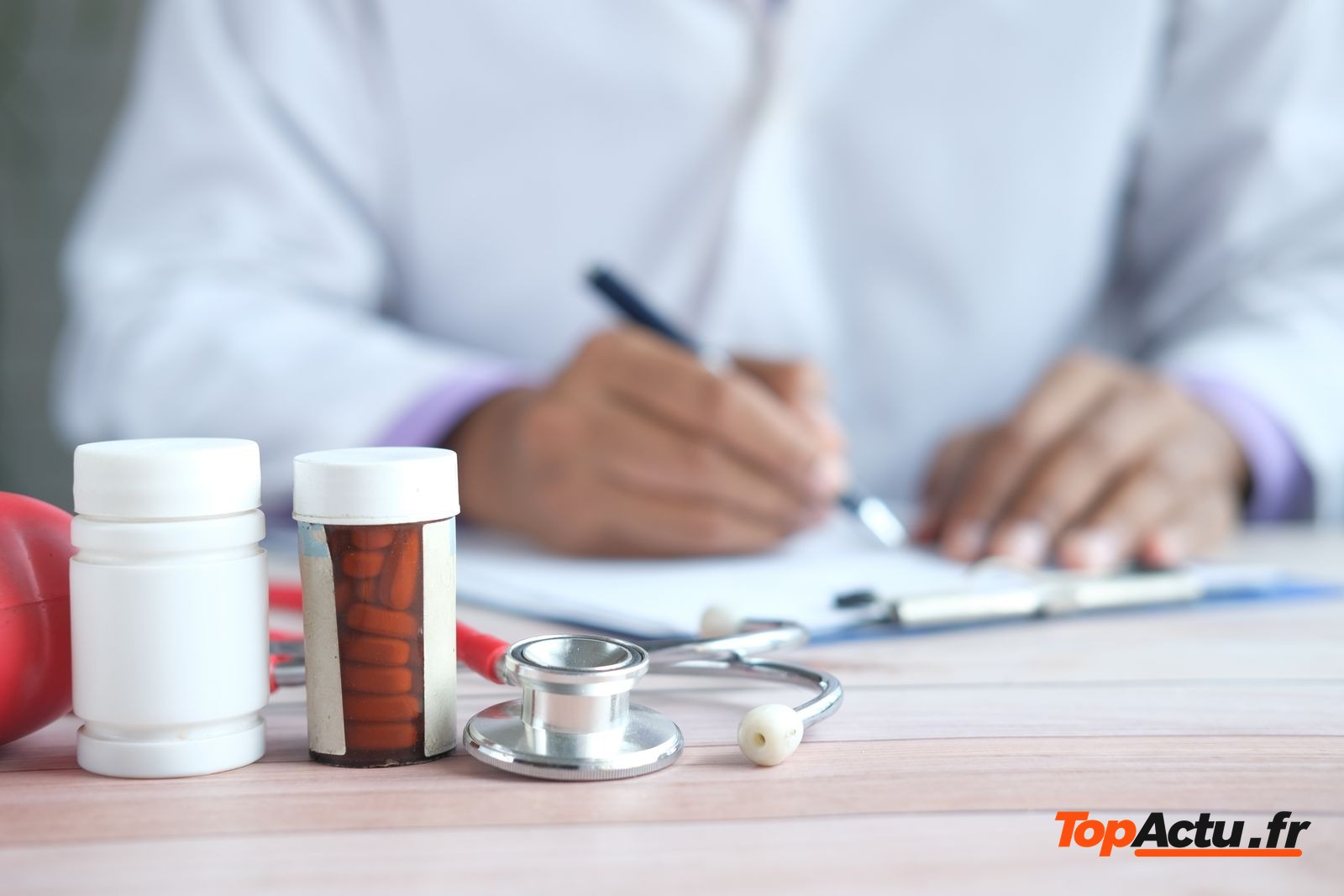 Médecin qui rédige un document à côté de flacons et d'un stéthoscope