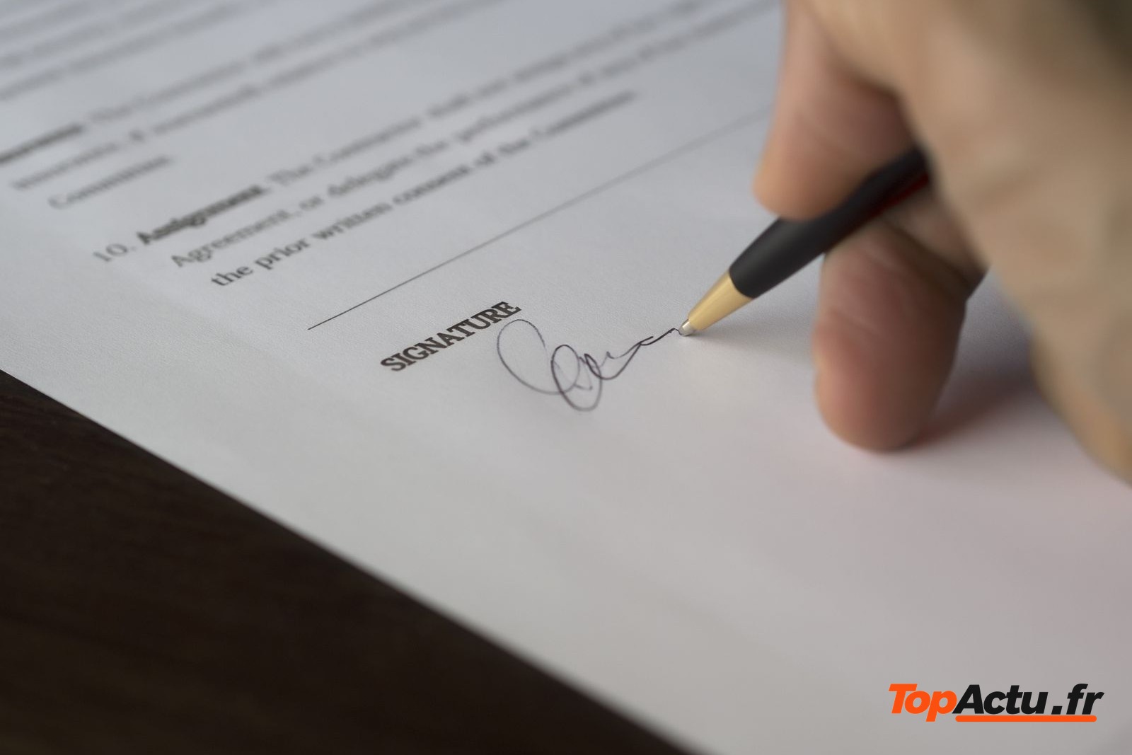 Main qui signe un document avec un stylo