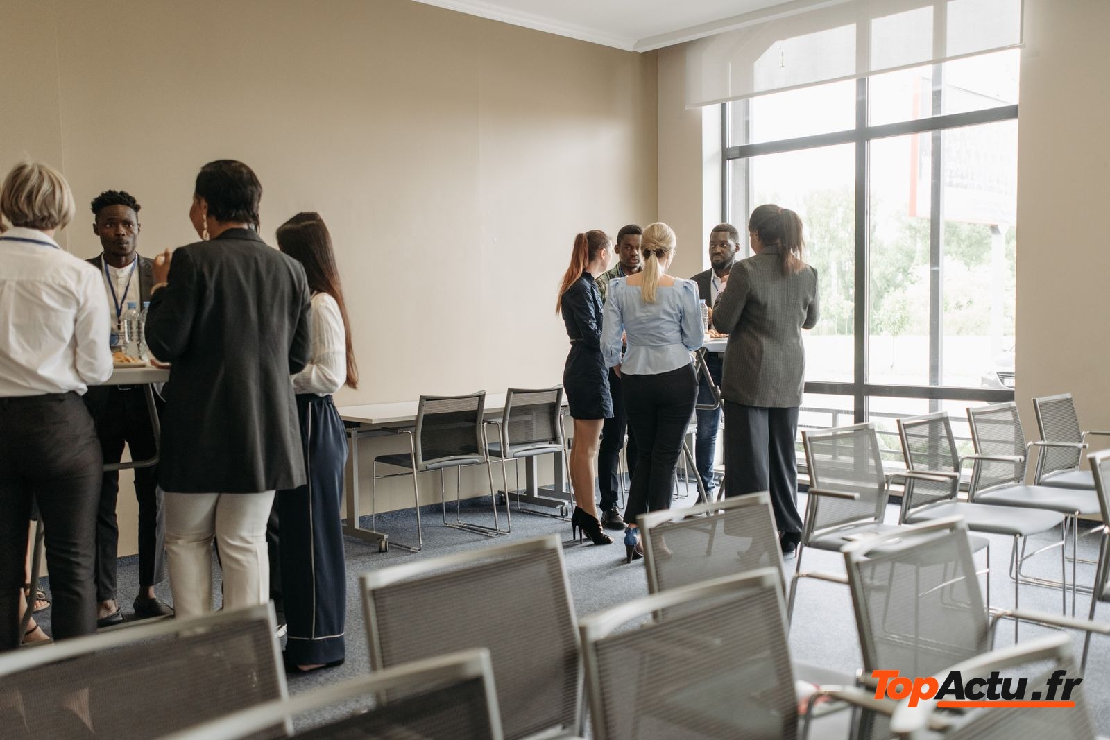 Personnes debout dans une salle de réunion avec des chaises