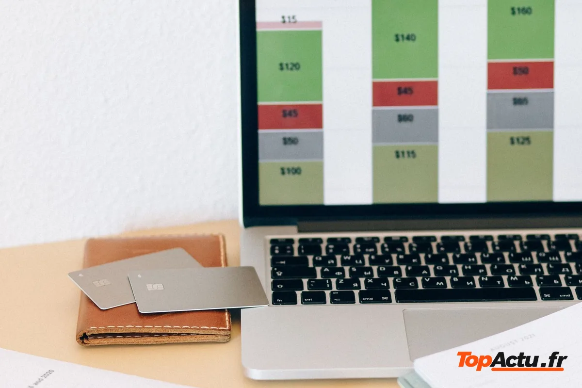 Ordinateur portable affichant un graphique de budget, avec un téléphone et des documents sur la table