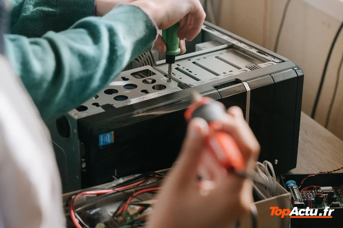 Deux personnes réparent le circuit électronique d'un appareil avec un tournevis
