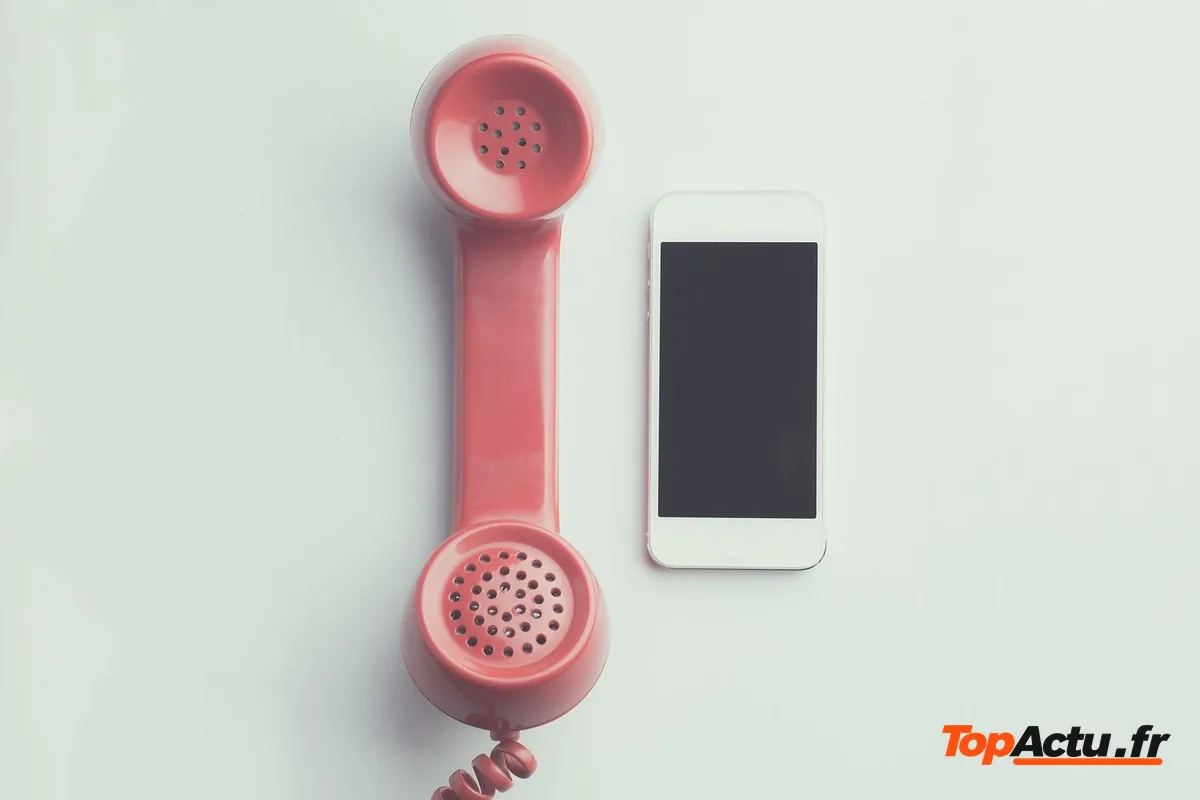 Un combiné de téléphone rétro rose posé à côté d'un smartphone sur un fond clair