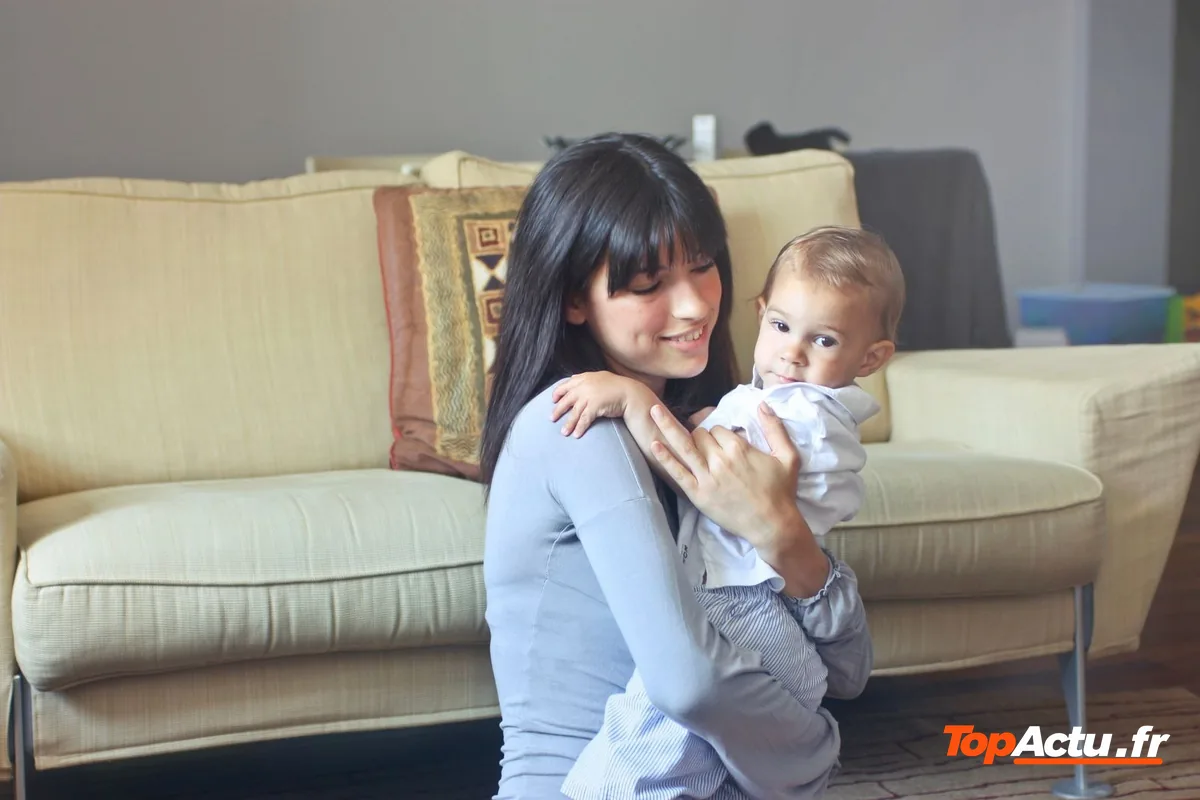 Une femme assise sur un canapé avec un bébé dans les bras