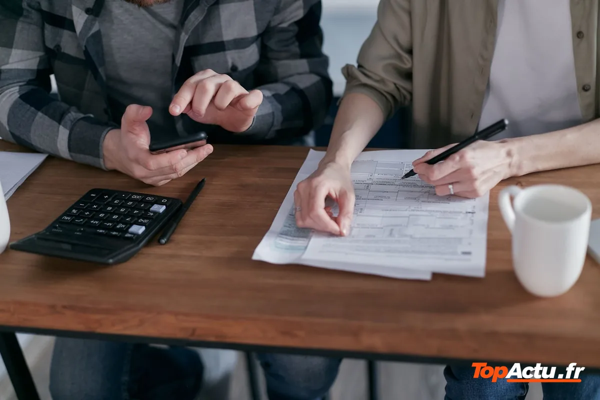 Deux personnes qui remplissent un formulaire avec une calculatrice et un smartphone