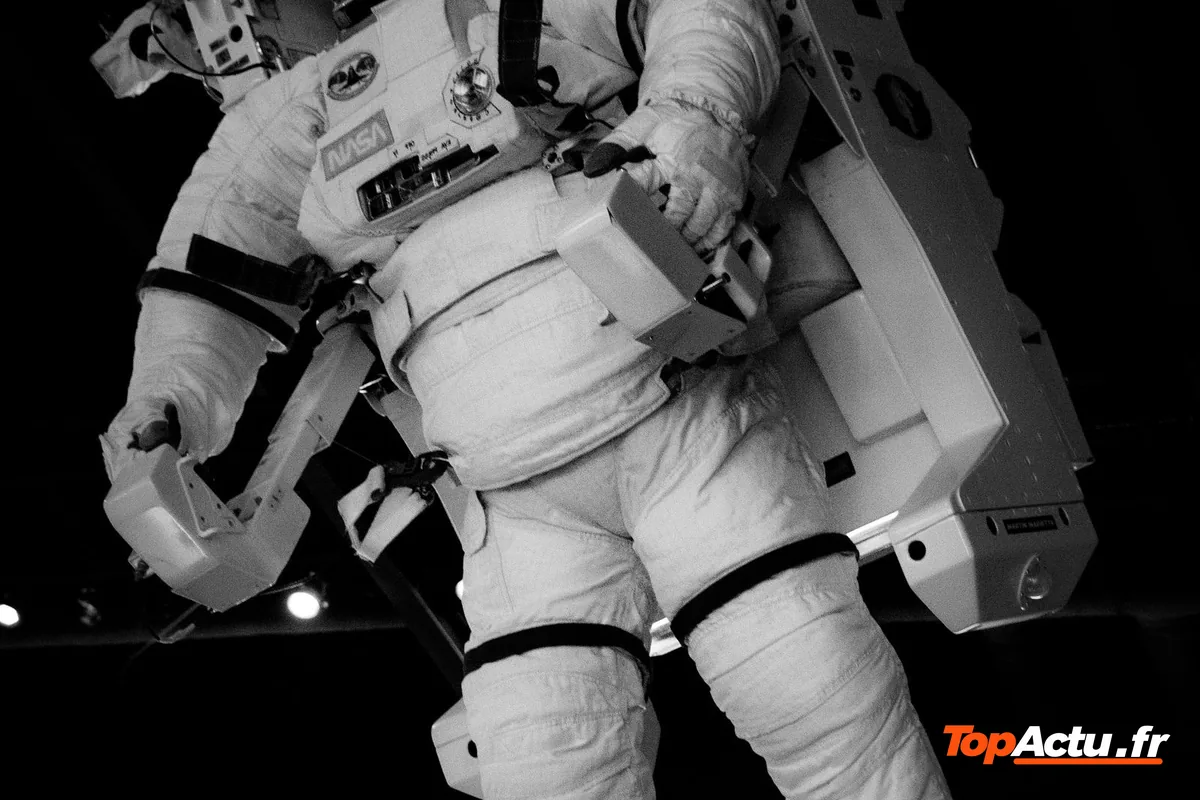 Astronaute en combinaison blanche flottant dans l'espace pendant une sortie extravéhiculaire, en noir et blanc