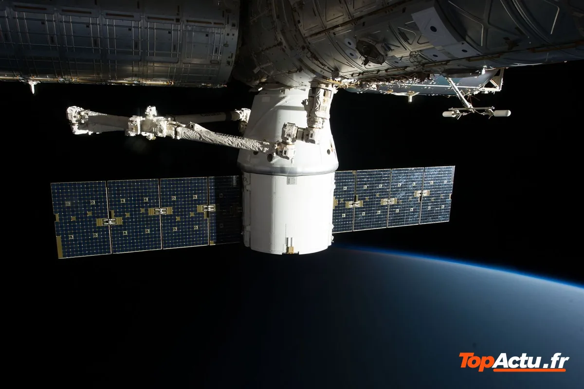 Capsule de ravitaillement amarrée à la station spatiale internationale, avec ses panneaux solaires, au-dessus de la Terre
