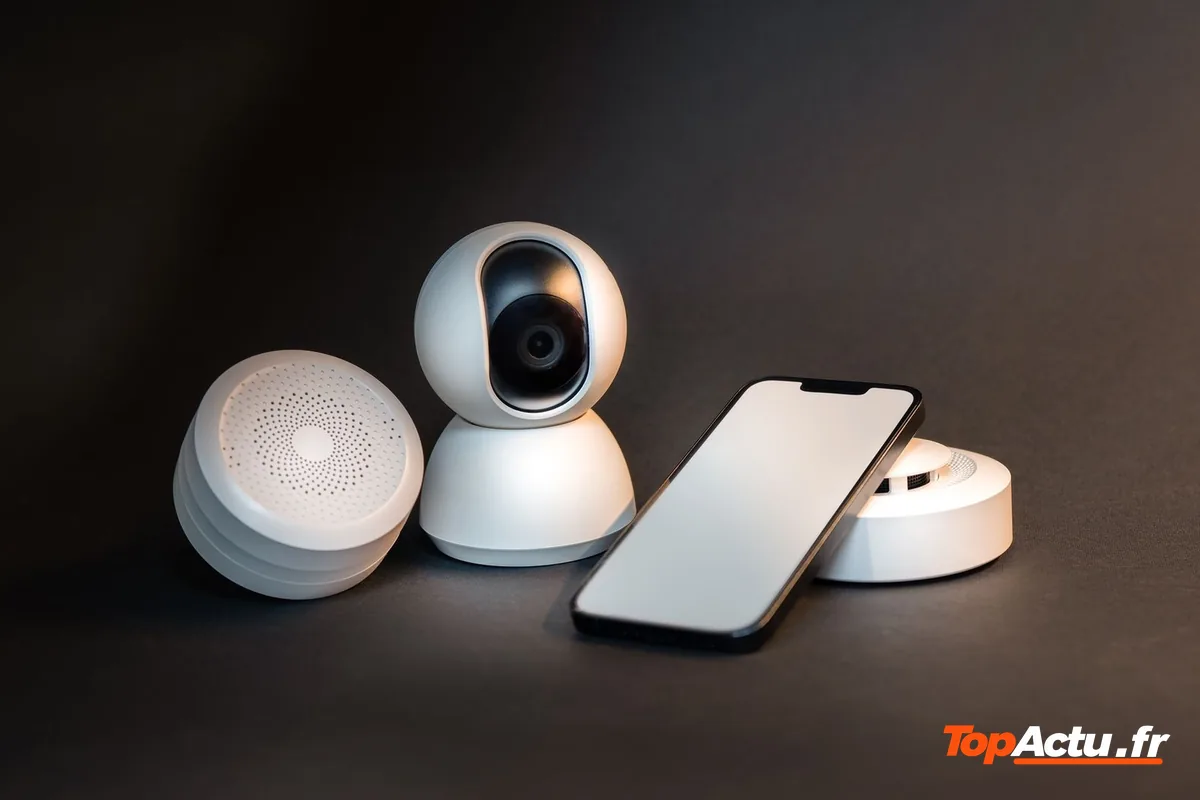 Une caméra connectée, un capteur et un smartphone posés sur un fond sombre
