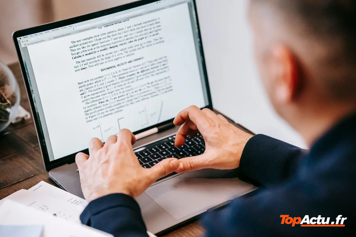 Un homme, vu de dos, tape un texte sur un ordinateur portable