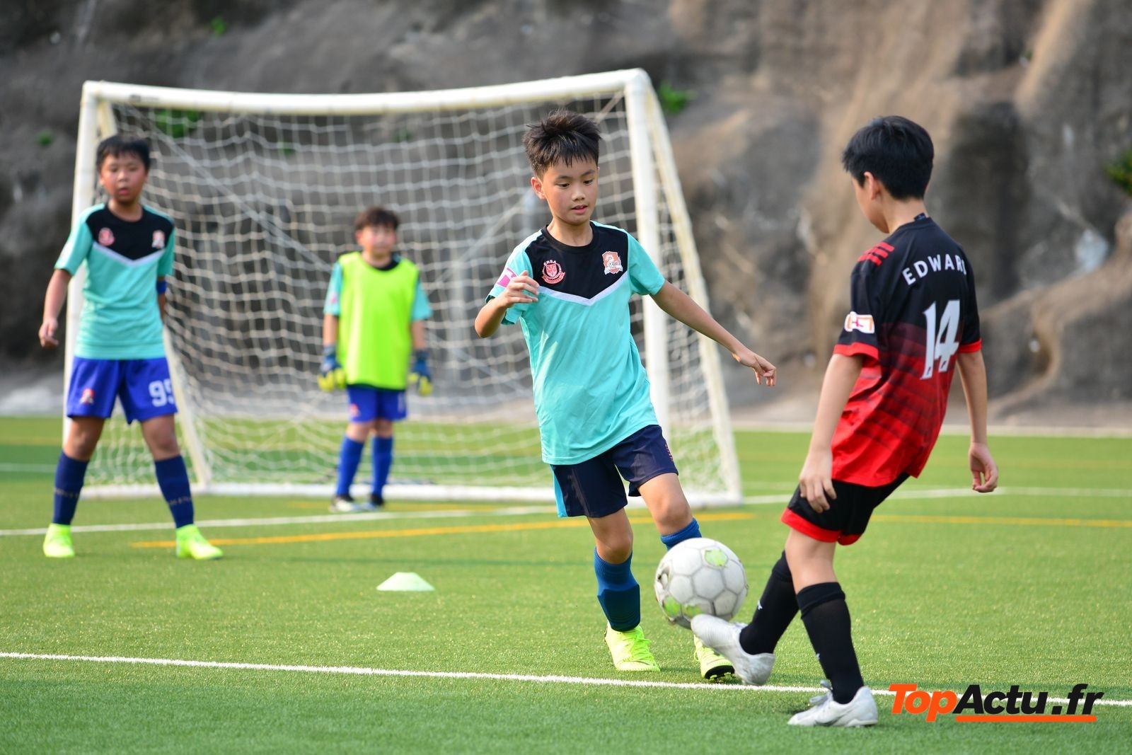 Enfants en tenue de football qui jouent devant un but sur un terrain de club