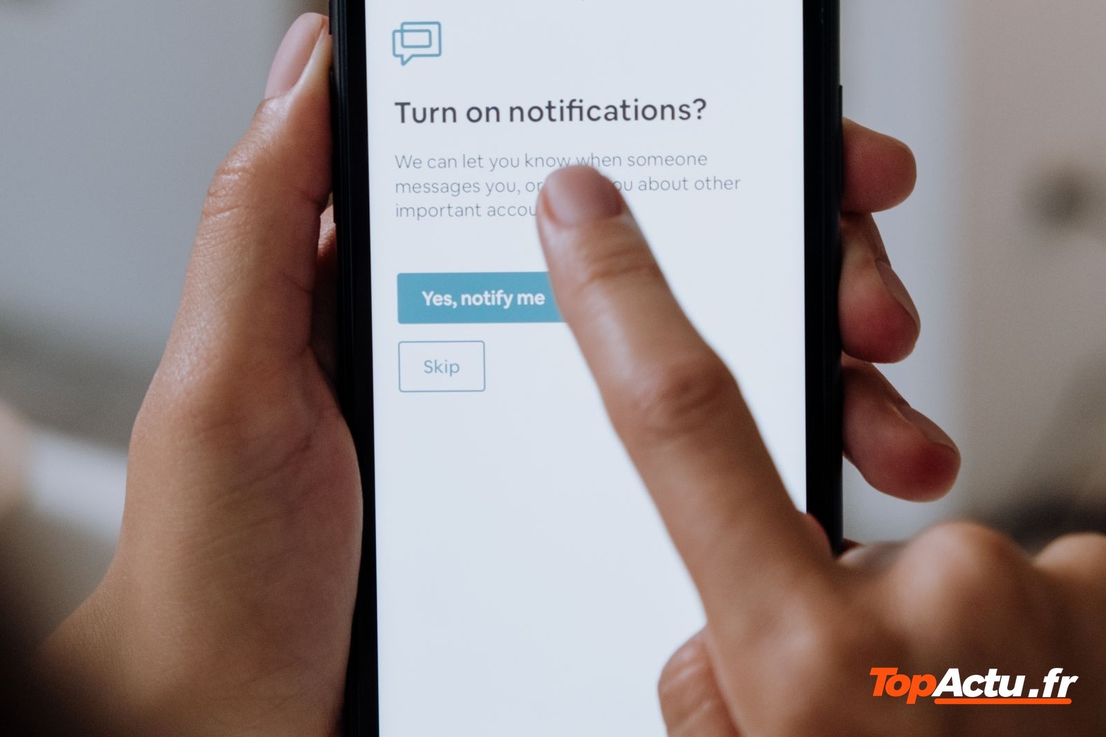 Mains qui touchent l'écran d'un smartphone affichant une demande d'autorisation des notifications