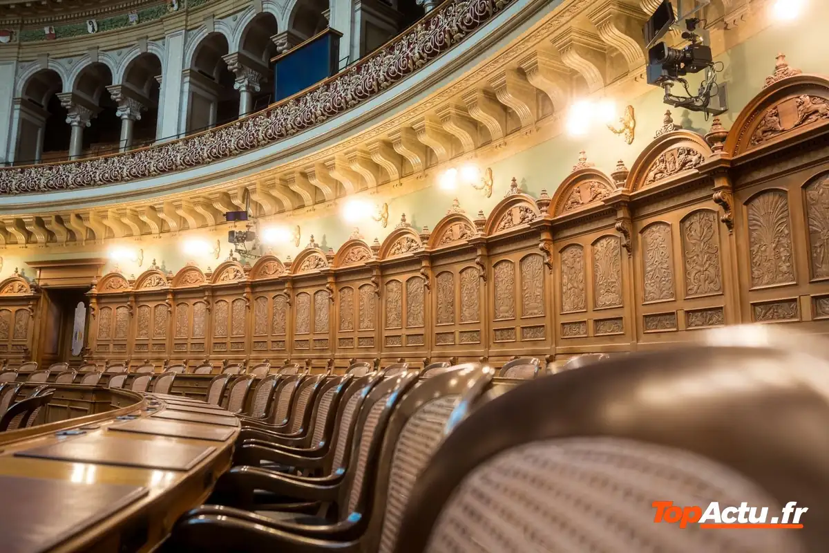 Hémicycle vide aux boiseries et fauteuils en cuir, vu depuis le côté