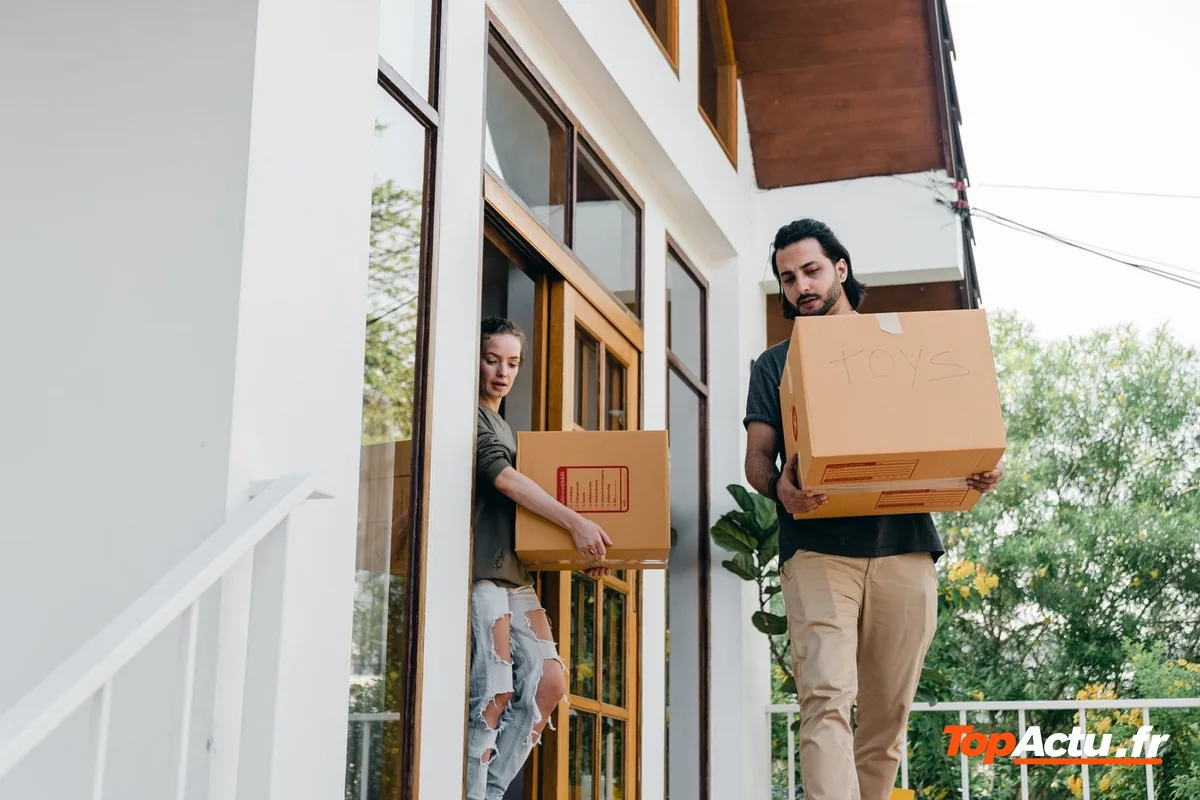 Un couple porte des cartons pour emménager dans une maison