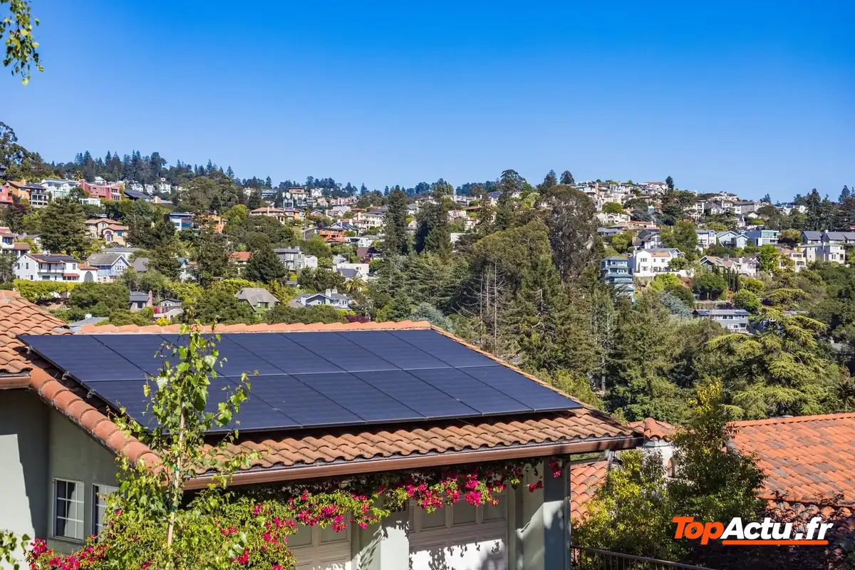 Un toit de maison équipé de panneaux solaires dans un quartier résidentiel au soleil