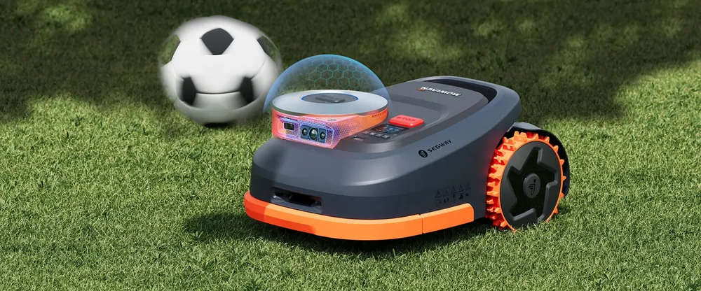 Une tondeuse robot Navimow orange et grise face à un ballon de football posé sur la pelouse