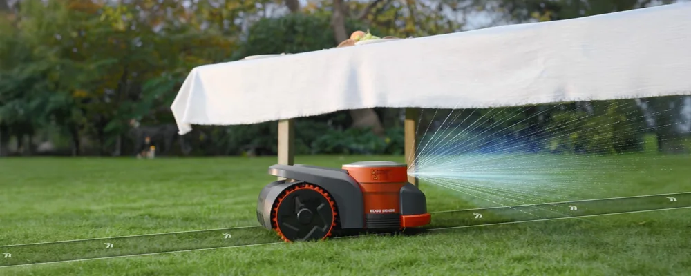 Une tondeuse robot Navimow qui passe sous une table recouverte d'une nappe, avec un faisceau de détection