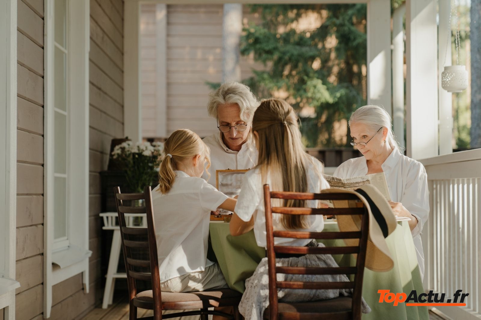 Grands-parents et petits-enfants attablés sur la véranda d'une maison