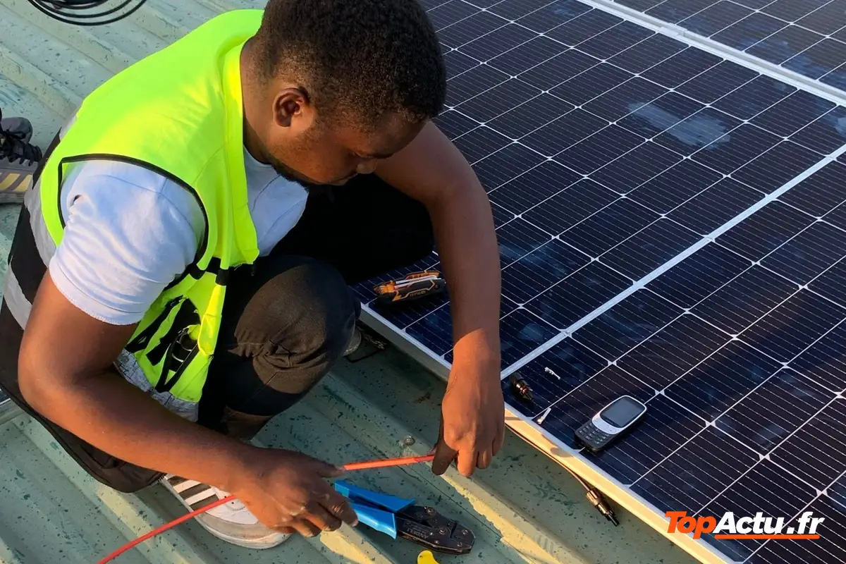 Un installateur en gilet fluo qui fixe des panneaux solaires sur un toit
