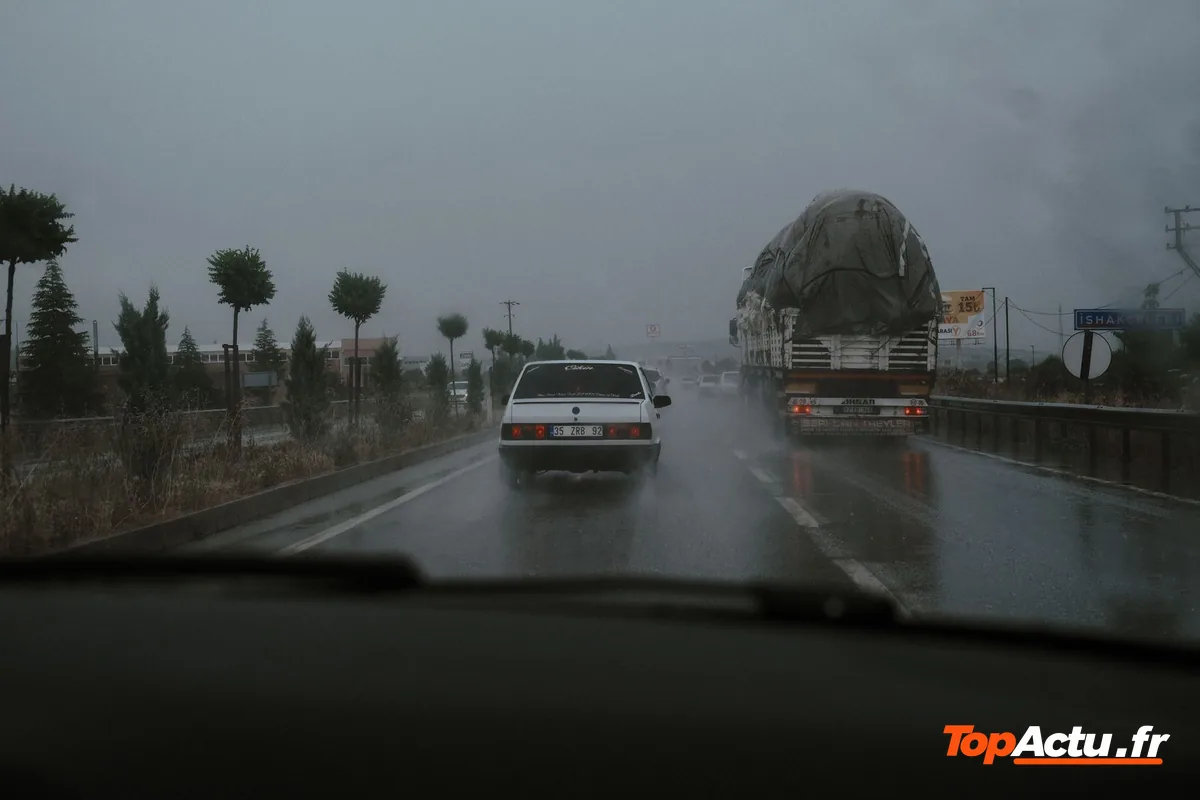 Voiture sur une route sous la pluie, vue à travers le pare-brise