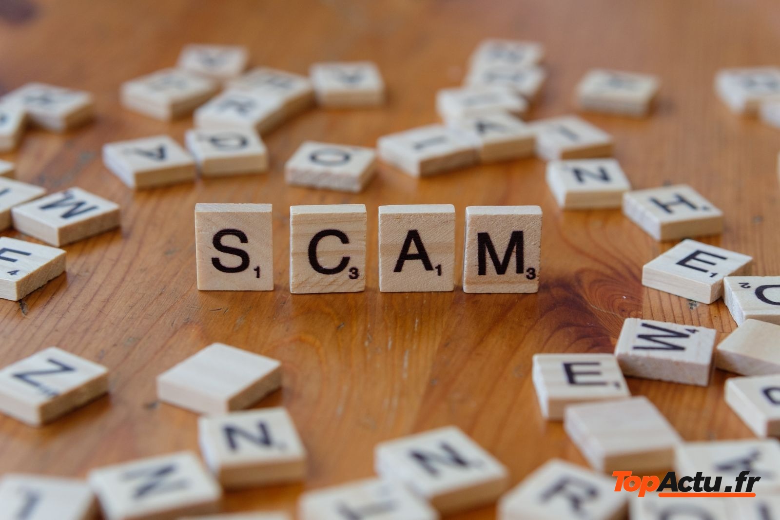 Lettres de jeu qui forment le mot SCAM sur une table en bois